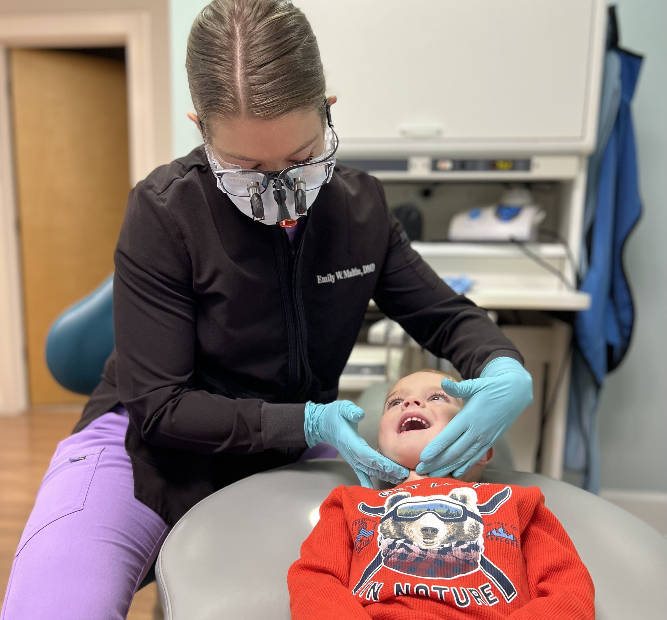 Dental hygienist examining a young patient's teeth during a checkup at ManiDental in Elkin, NC.