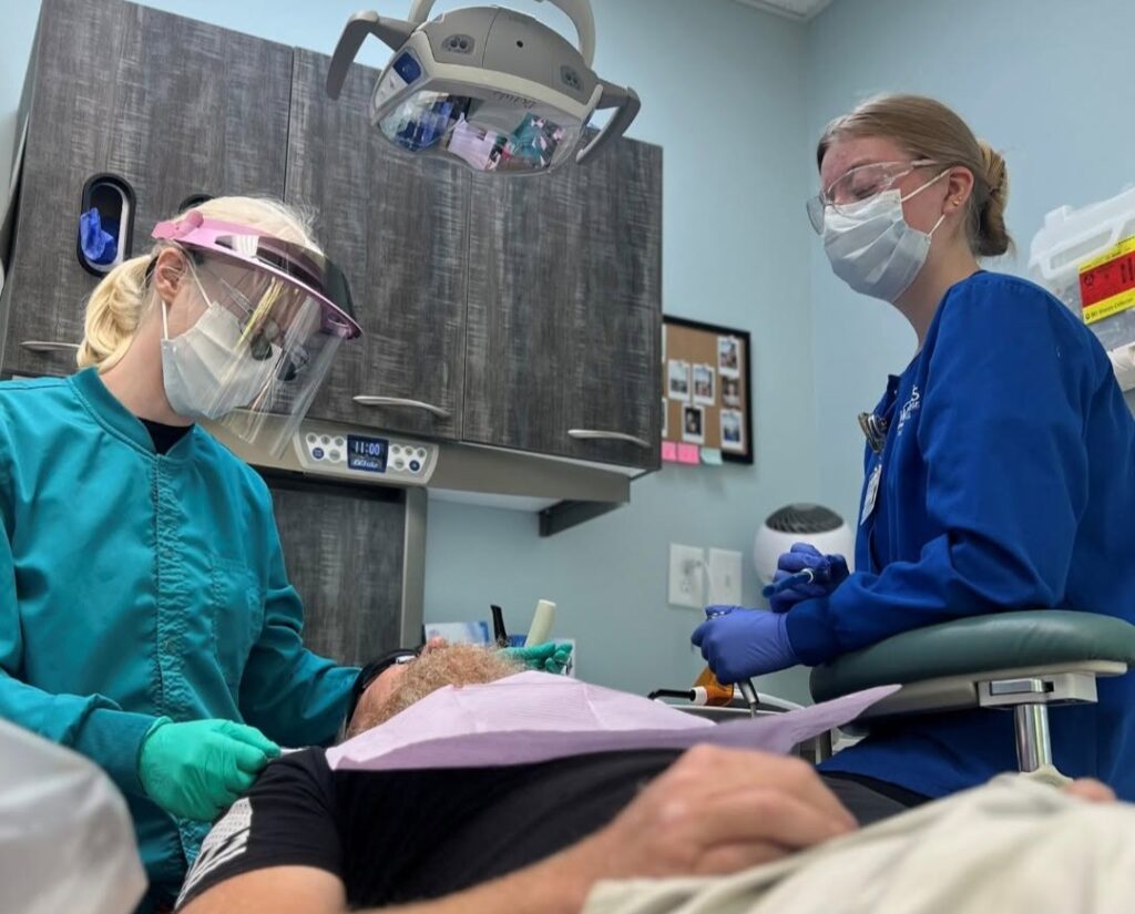 Dr. Manigault and a dental assistant performing periodontal treatment on a patient.
